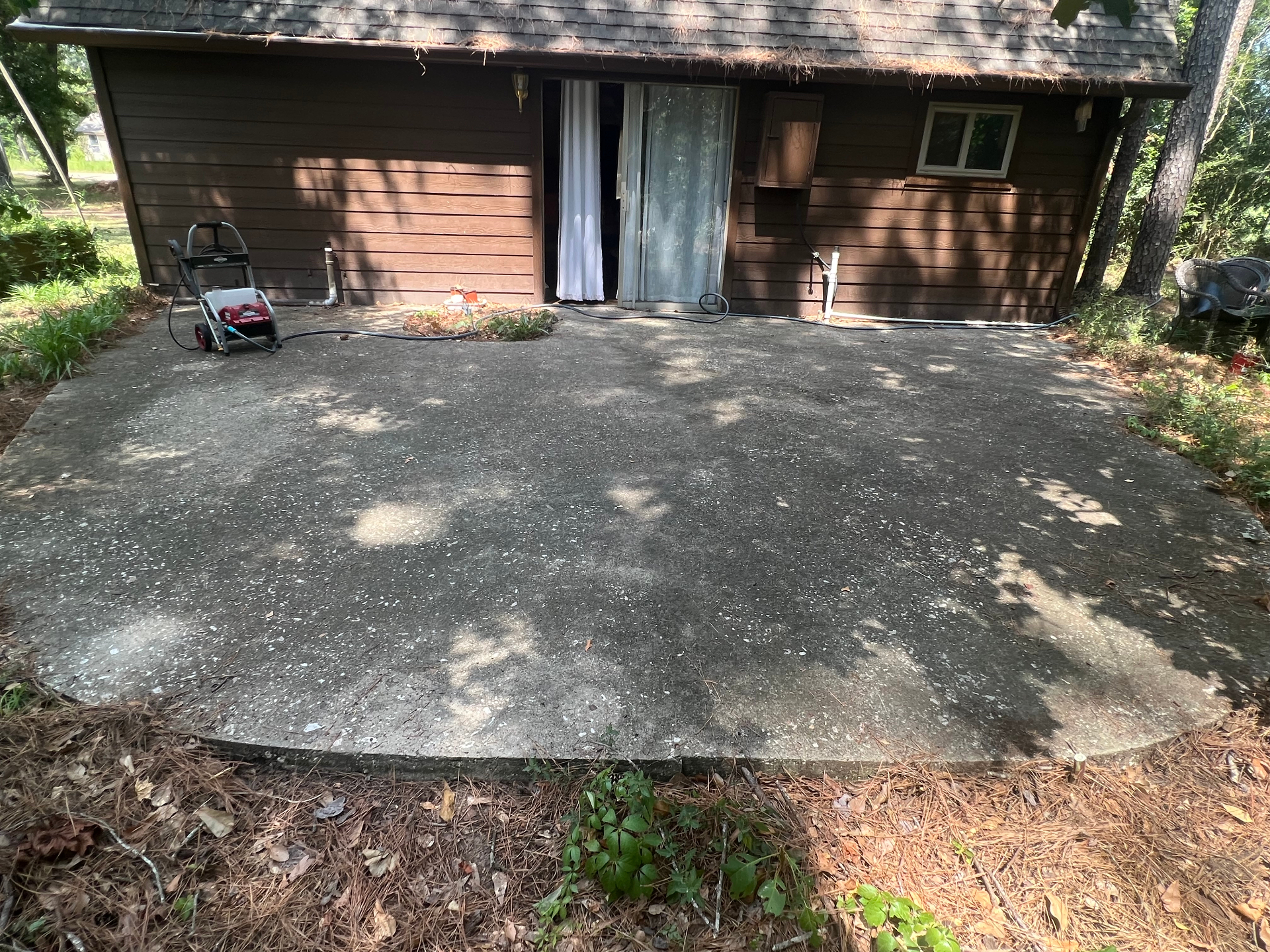 Dirty untreated concrete patio before cleaning, July 2023